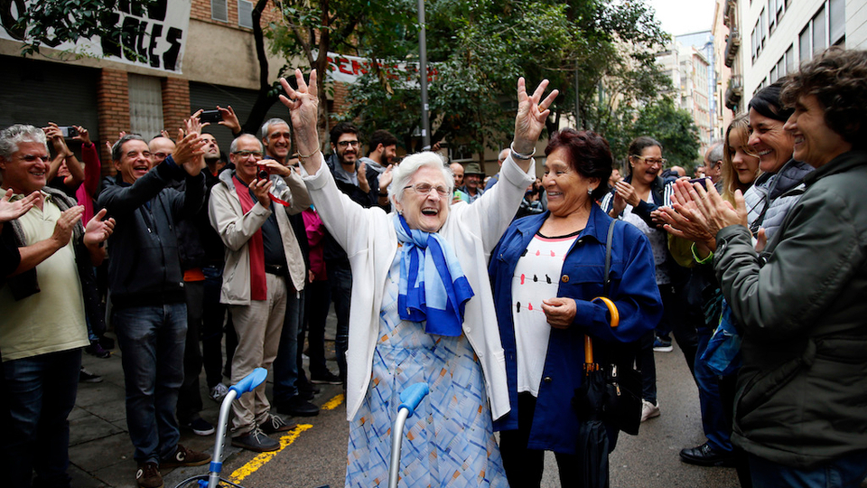 In this Sunday, Oct. 1, 2017 photo, an elderly lady is applauded as she celebrates after voting at a school assigned to be a polling station by the Catalan government at the Gracia neighborhood in Barcelona, Spain.