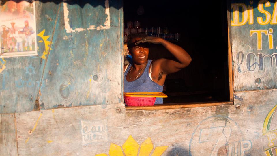 A woman looks out from her vendor's stall where she sells milk, charcoal, oil and rice in the Delmas tent camp set up seven years ago for people displaced by the 2010 earthquake, in Port-au-Prince, Haiti. (File Photo AP)