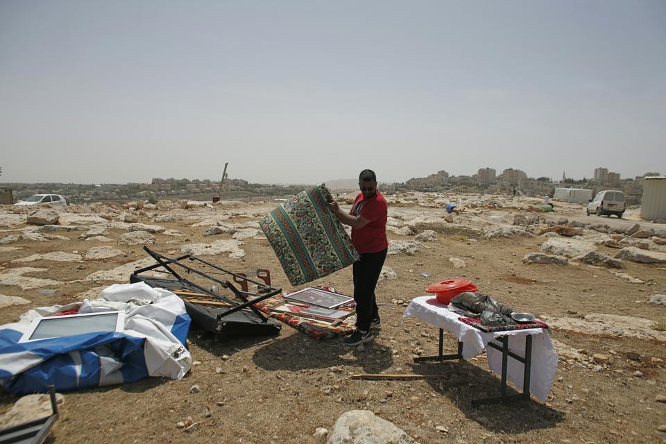 A Palestinian Bedouin man collects his belongings after Israeli Army forces dismantled a number of prefab houses, built with a donation from the European Union, in the West Bank Area B town of Al Azariya, east of Jerusalem, on May 16, 2016. (AFP)