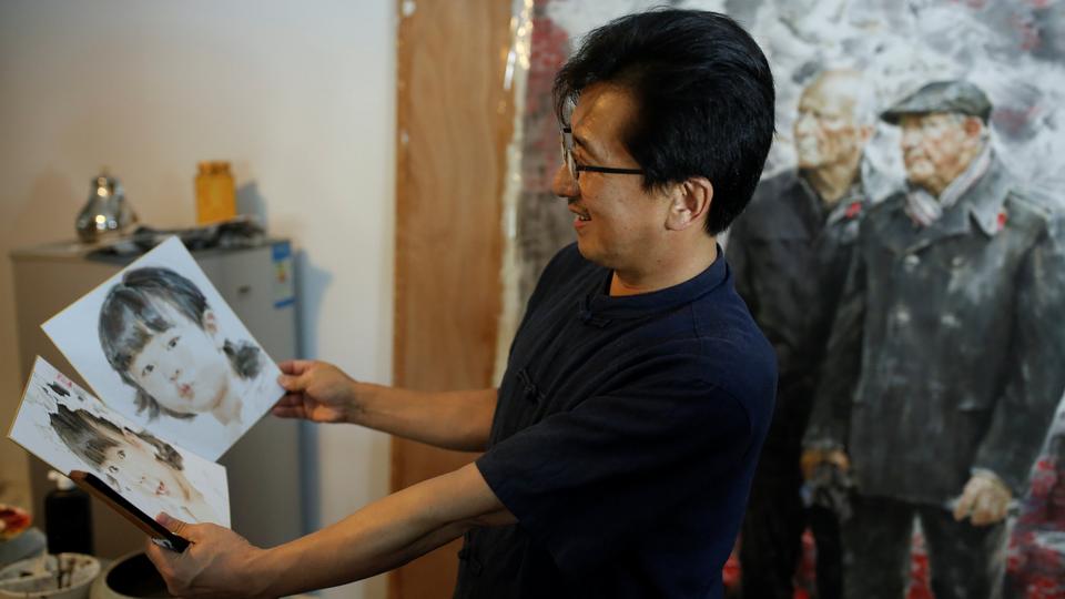 The head of the Mansudae Art Museum Ji Zhengtai talks about paintings by a North Korean artist in the studio of the gallery in Beijing. September 20, 2017.