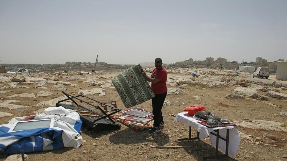 A Palestinian Bedouin man collects his belongings after Israeli Army forces dismantled a number of prefab houses, built with a donation from the European Union, in the West Bank Area B town of Al Azariya, east of Jerusalem, on May 16, 2016. (AFP)